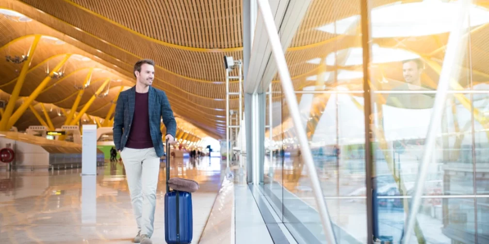 Hombre caminando en el aeropuerto con maleta